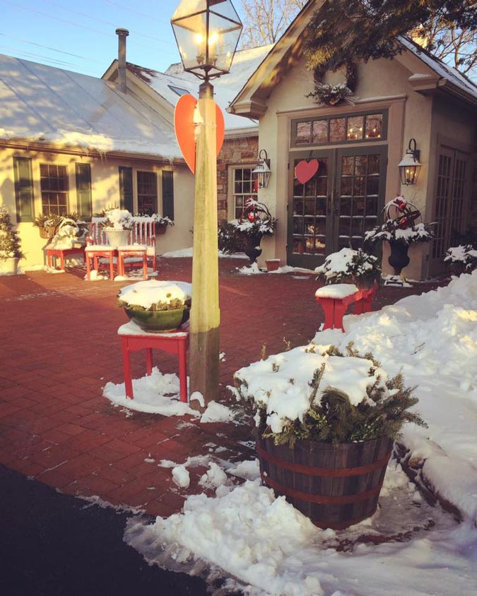 The front of the store is covered in snow and there are red hearts hanging on the double doors.
